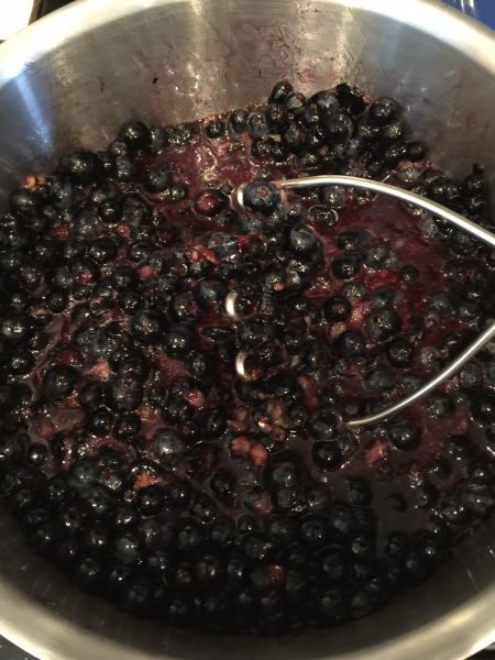 mashing blueberries for jam